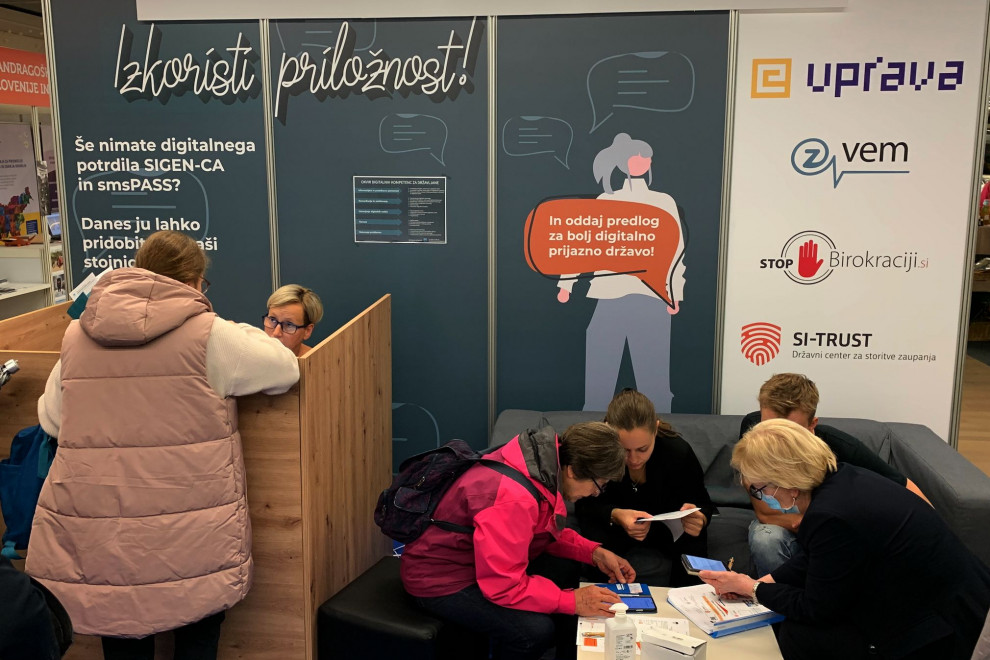 Obiskovalka stoji pred pultom in izpolnjuje podatke.