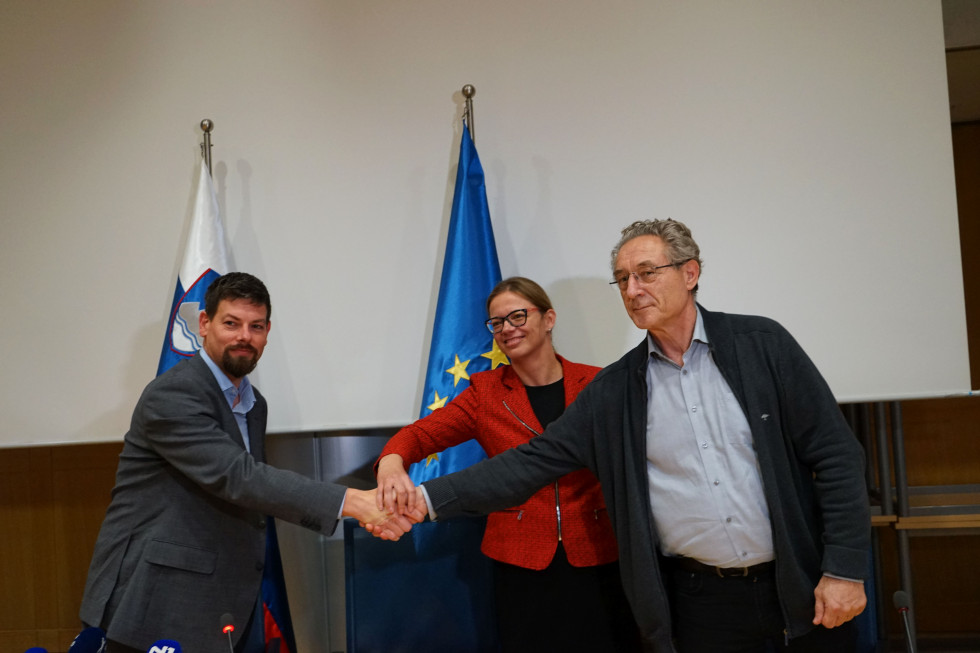 In the photo: Minister Sanja Ajanović Hovnik, and the heads of the negotiating teams of representative public sector unions, Branimir Štrukelj and Jakob Počivavšek, shaking hands, with the Slovenian and EU flags in the background.