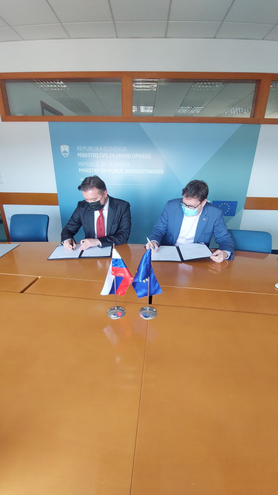 Boštjan Koritnik in dr.Mirko Pečarič sedita za mizo, podpisujeta dokument, ki je pred vsakim od njiju v odprti mapi