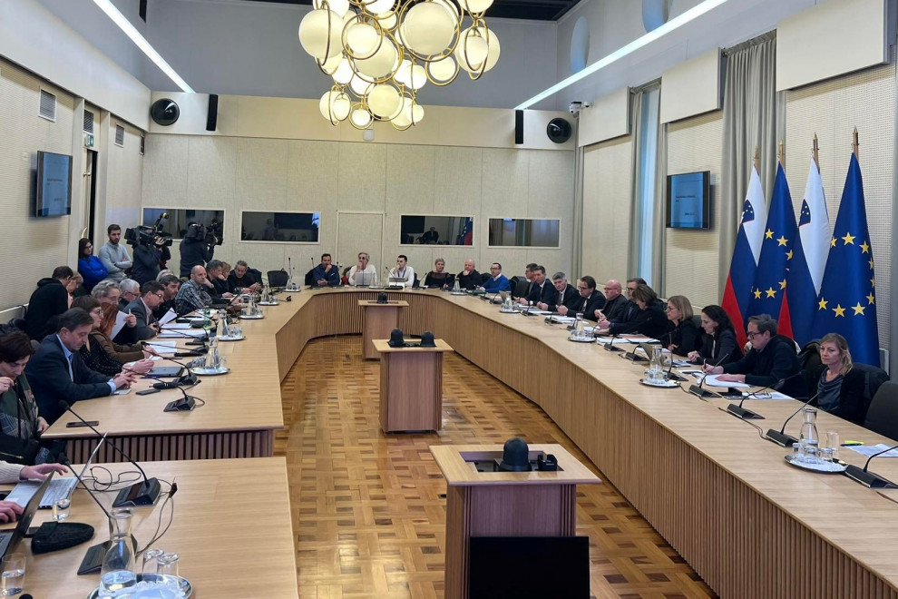 člani pogajalskih skupin sedijo za ovalno mizo