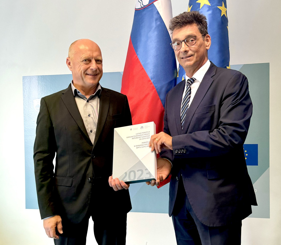 Minister in varuh človekovih pravic se rokujeta ob predaji poročila