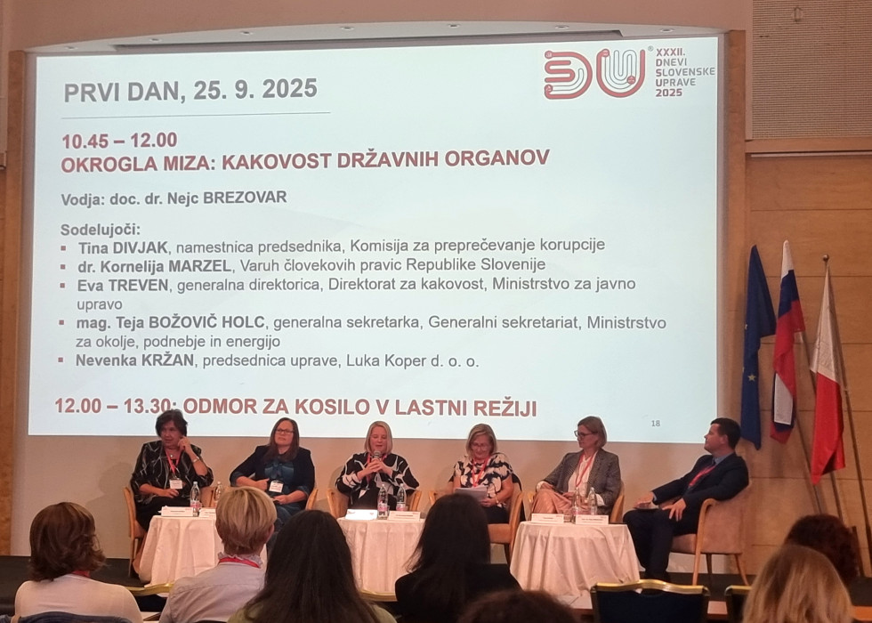 sodelujoči v okrogli mizi sedijo na odru in razpravljajo