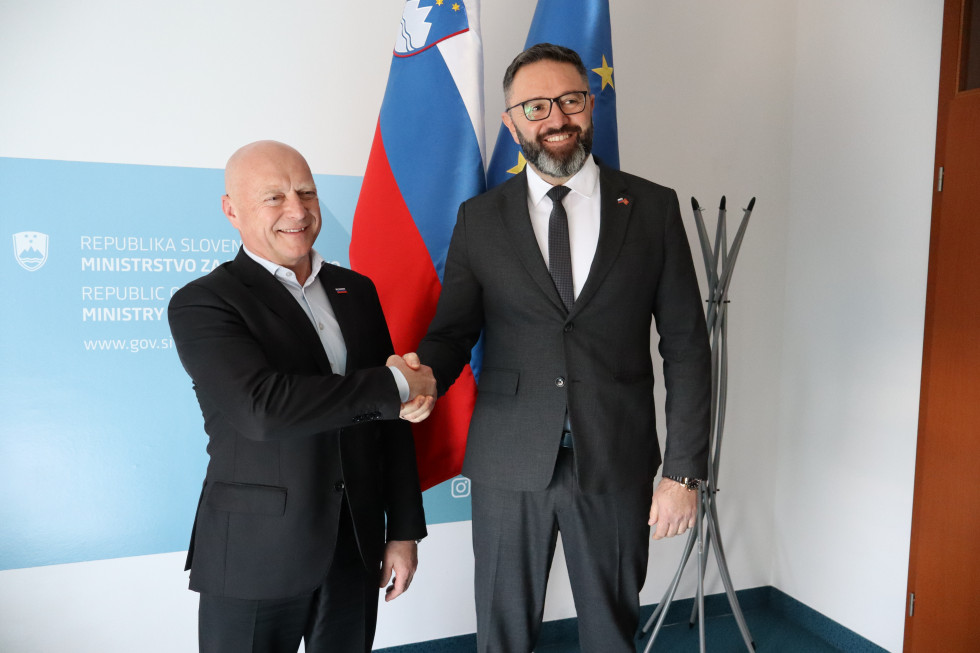 Minister in veleposlanik se rokujeta pred slovensko in evropsko zastavo