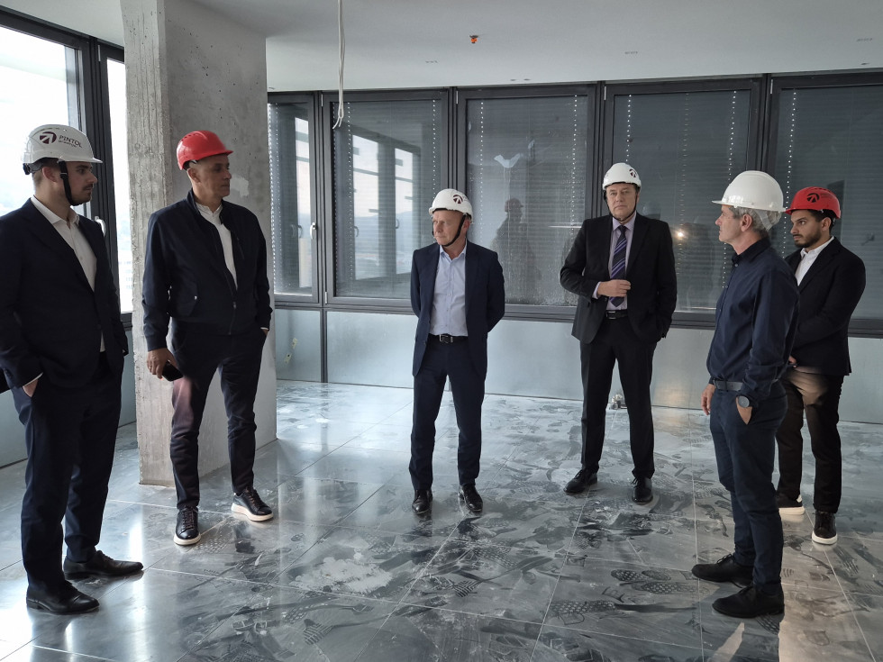 Ljudje stojijo v praznem prostoru, ki je še v gradnji. 