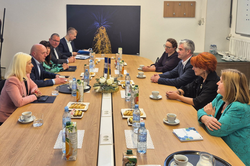 Ljudje sedijo na levi in desni strani velike rjave mize.