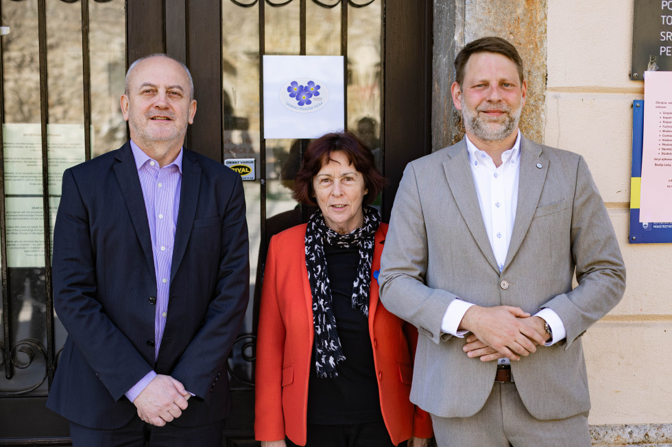 Trije predstavniki stojijo pred vhodom upravne enote ob oznaki demenci prijazne točke.