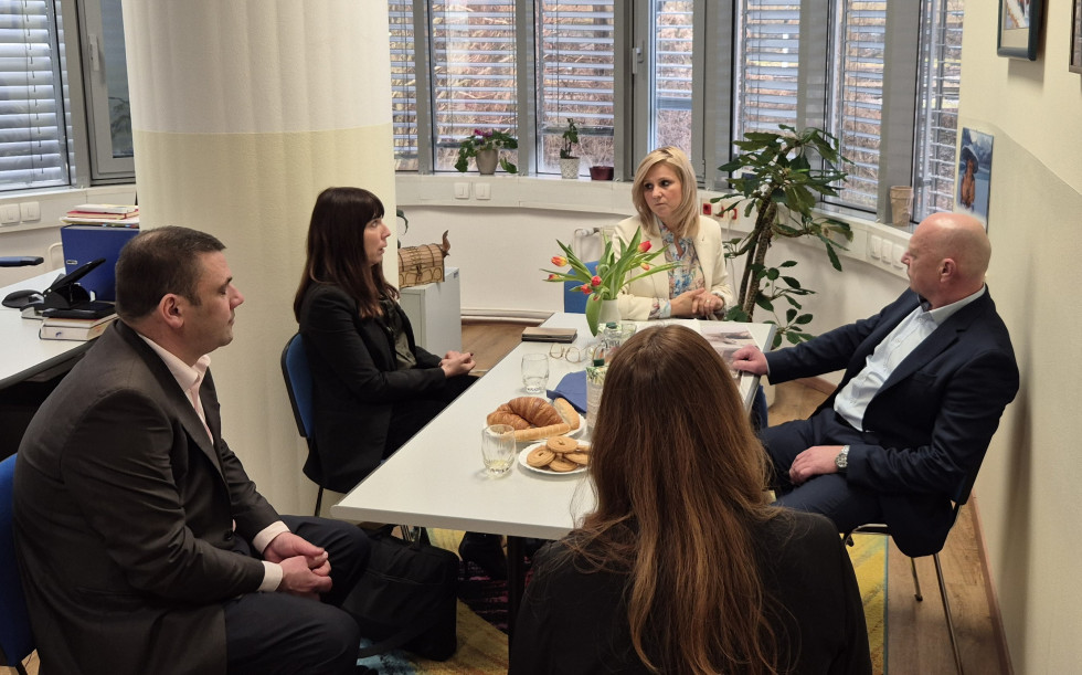 Ljudje sedijo za mizo in se pogovarjajo. 