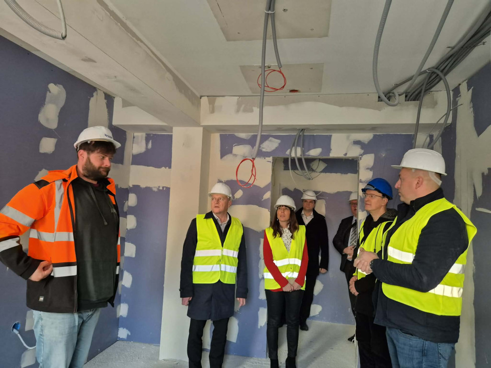 Minister mag. Franc Props s sodelavci in predstavniki izvajalcev v zaščitnih čeladah in odsevnih jopičih spremlja ogled poteka obnovitvenih del v objektu Upravne enote Krško.