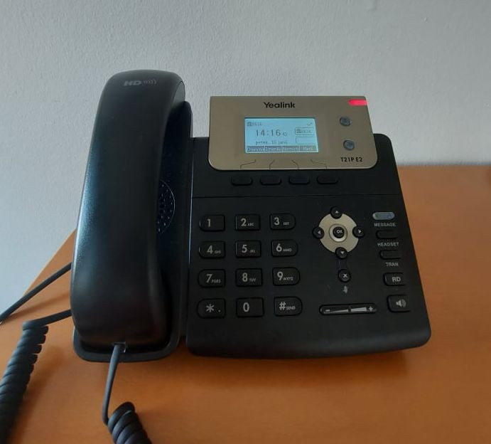 na pisalni mizi je klasični telefon črne barve, utripa rdeča lučka