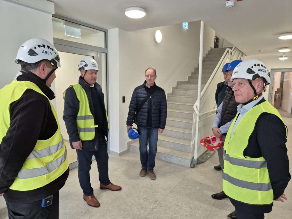 Ljudje stojijo v krogu pred stopniščem in se pogovarjajo.