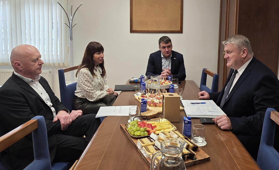 Ljudje sedijo za rjavo mizo in se pogovarjajo.