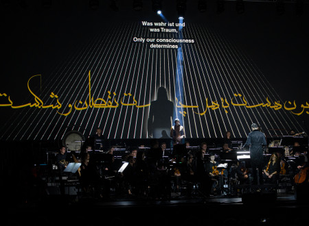 Vokalist Laibach Milan Fras na odru pod svetlobnim napisom