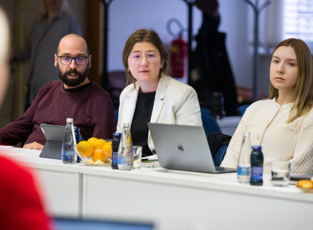 Trije predstavniki mladinskih organizacij sedijo za mizo, pred njimi prenosni računalniki