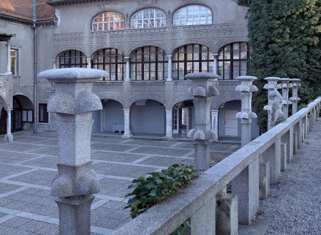 Preddverje oziroma glavno dvorišče Križank s kamnitimi stebrnimi svetilkami ter z avtonomno prizidanima fasadama z arkadnim hodnikom v ozadju.
