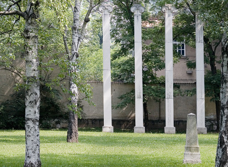 Pokopališče Navje v Ljubljani s štirimi Plečnikovimi stebri v ozadju in tremi vrbami v ospredju.