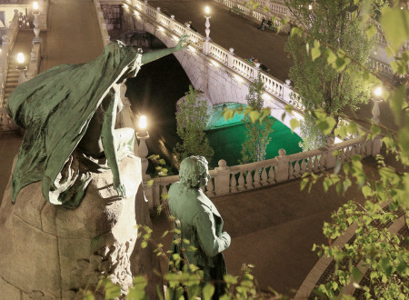 Oddaljen nočni pogled navzdol na Prešernov kip in dva od treh mostov Tromostovja.
