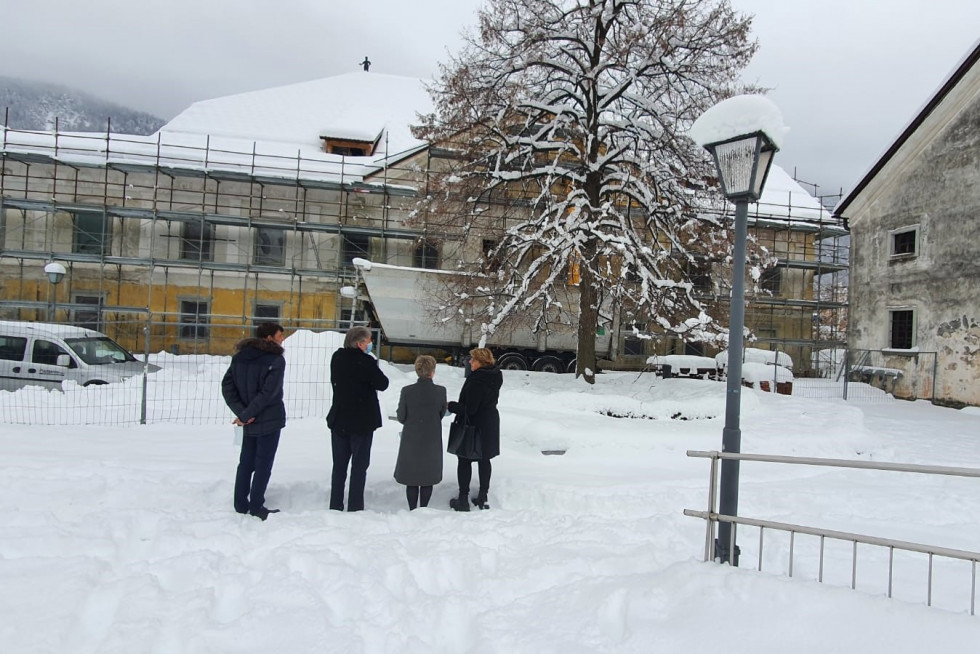 Minister za kulturo skupaj s predstavniki občine Jesenice pred s snegom pobeljeno Ruardovo graščino z gradbenim odrom