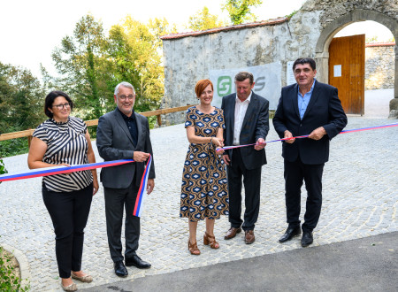 Ministrica z kulturo v roki drži prerezan otvoritveni trak