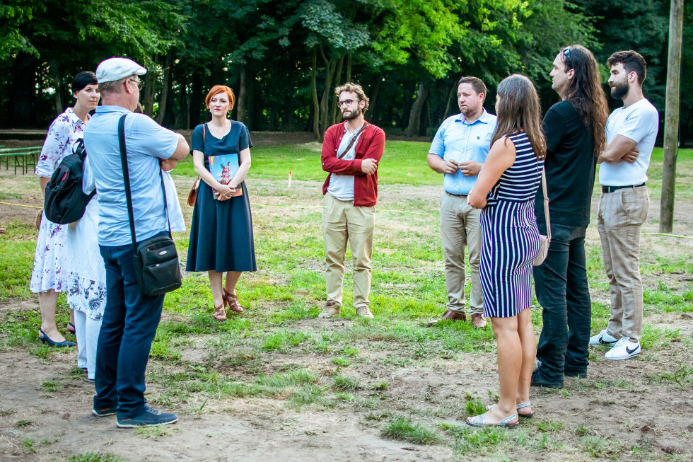 Skupinska fotografija ljudi, ki stojijo v krogu, na travniku