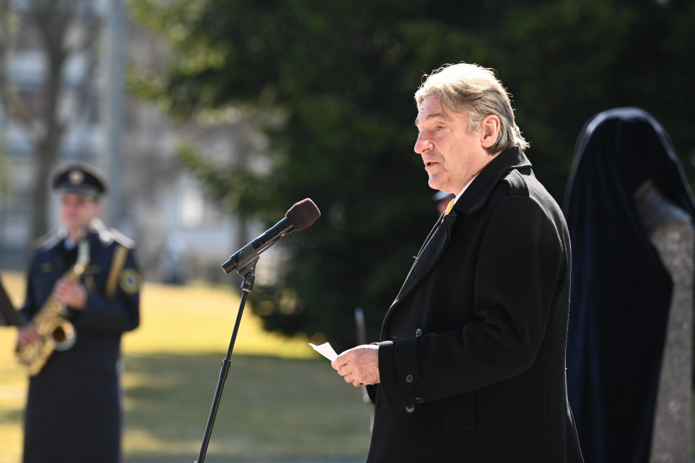 Minister za kulturo stoji pred mikrofonom in nagovarja zbrane na slovesnosti ob odkritju doprsnega kipa dr. Jožeta Pučnika