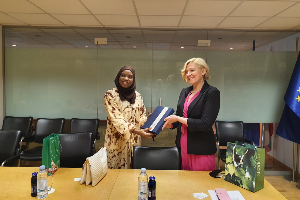 Nasmejana nigerijska veleposlanica prejema darilo ministrstva za kulturo, ki ji ga izroča nasmejana državna sekretarka