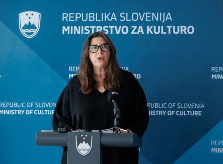 Direktorica Muzeja za arhitekturo in oblikovanje stoji za govorniškim odrom in nagovarja zbrane