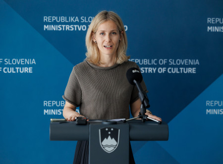 So-avtorica slovenskega paviljona stoji za govorniškim odrom in nagovarja zbrane