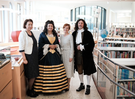 Direktorica in ministrica za kultuo med knjižnimi policami v družbi z žensko in moškim, ki je oblečen v Valvasorja