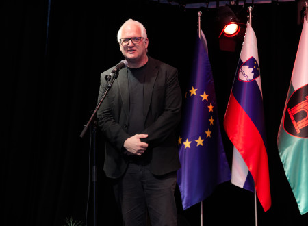 Državni sekretar stoji pred mikrofonom, na njegovi levi zastavi Evropske unije in Slovenije