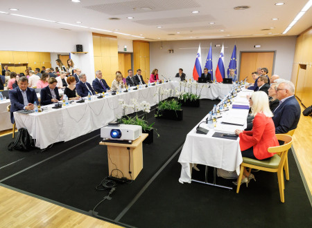 Ministri sedijo za mizami, ki so postavljene v u obliki in prekrite z belimi prti