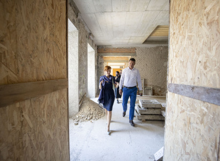Ministrica in župan hodita po notranjem prostoru dvorca, ki je sredi gradbeno obnovitvenih del