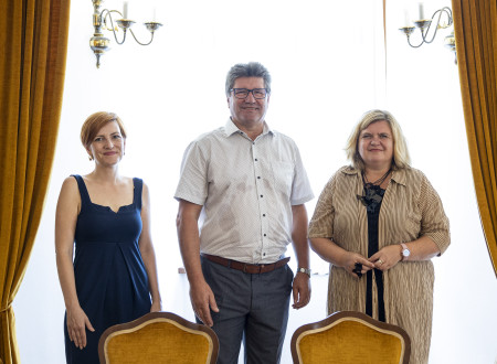 Ministrica, župan in direktorica stojijo za mizo, za njimi oken