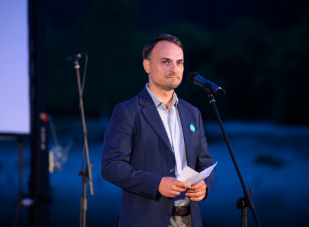 Generalni direktor stoji pred mikrofonom in nagovarja zbrane na večer premiere