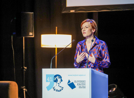 Ministrica za kulturo stoji za govornim odrom, na katerem je napis Slovenski knjižni sejem  