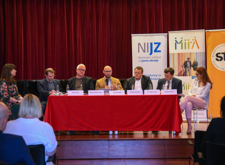 Udeleženci okrogle mize sedijo drug ob drugem med razpravo