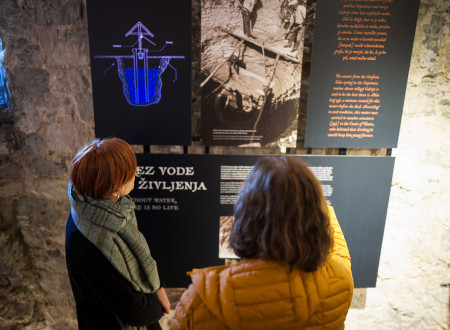 Ženska ministrici za kulturo pojasnjuje, kaj prikazuje fotografija na predstavitveni tabli v notranjosti gradu