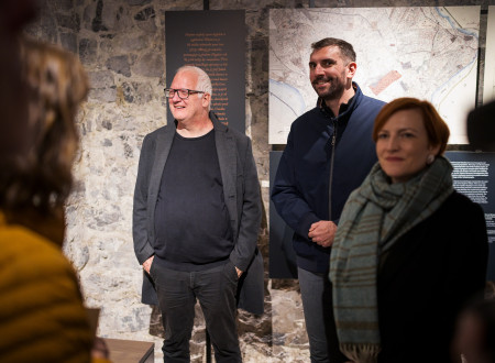 Državni sekretar in ministrica za kulturo v družni z nasmejanim moškim stojita v notranjosti prenovljenega gradu