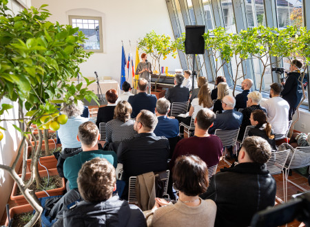 Ministrica za kulturo v osončeni oranžeriji nagovarja zbrane