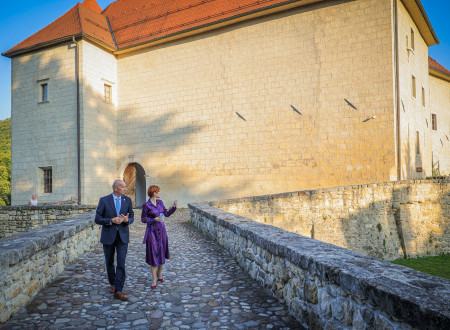 Župan in ministrica za kulturo se sprehajata po tlakovanem mostu, ki vodi do grajskega vhoda