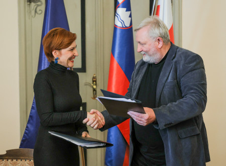 Ministrica in župan se rokujeta in v roki držita mapi s podpisano pogodbo