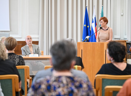 Ministrica za kulturo stoji za govorniškim odrom in nagovarja zbrane
