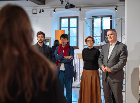 Avtorja projekta, ministrica in minister stojijo v velikem svetlem razstavnem prostoru,v ozadju dve visoki okni