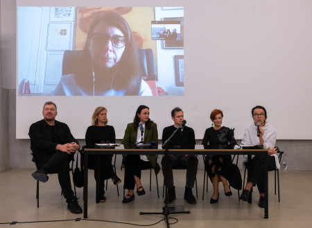 Dva udeleženca in štiri udeleženke novinarske konference sedijo za mizo, za njimi na platnu še šesta udeleženka, ki se jim je pridružila prek videa