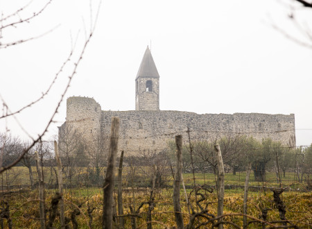 Obzidje, izza katerega se dviga cerkveni stolp z nišo, v kateri je zvon