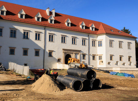 Pred vhodom v grad Negovo so na kup zložene črne velike cevi, tla so peščena, tik pred vhodom tovornjak.
