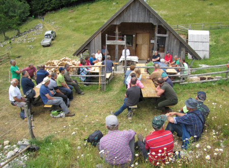 Skupina ljudi sedi pred leseno kočo