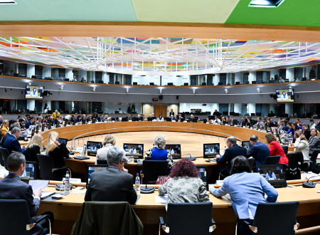 Udeleženci sedijo za mizami in sodelujejo na sestanku v veliki konferenčni dvorani.
