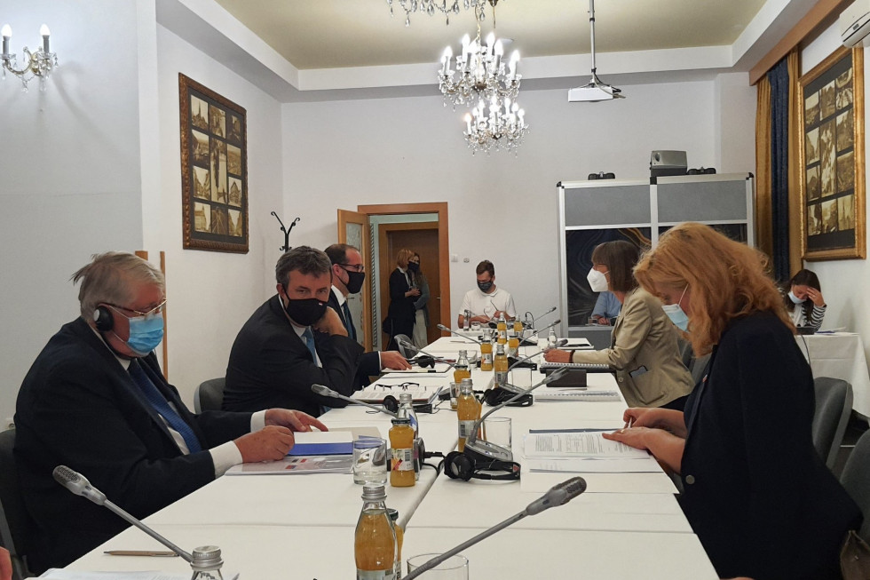 Udeleženci slovensko–madžarskega bilateralnega srečanja za mizo v zaprtem prostoru.