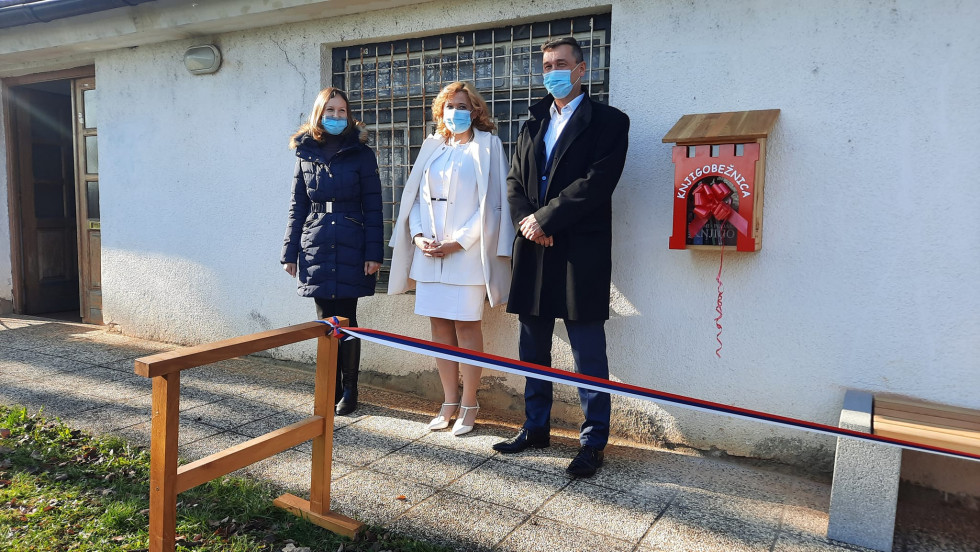 Državna sekretarka stoji ob knjigobežnici skupaj z direktorico knjižnice Črnomelj in podžupanom Občine Črnomelj 