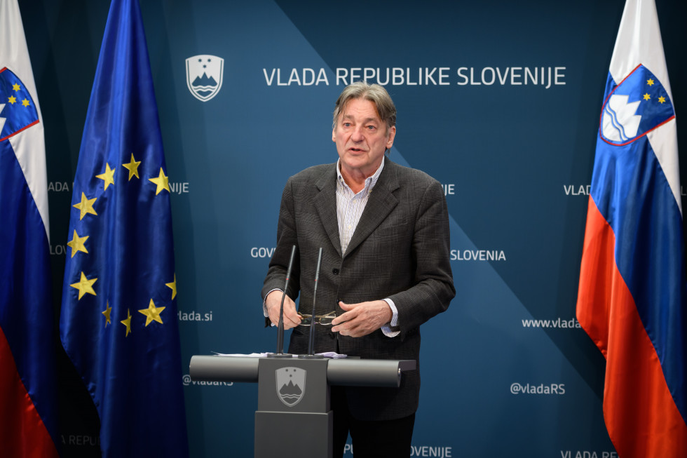 Minister stoji med izjavo v vladnem uradu za komuniciranje 